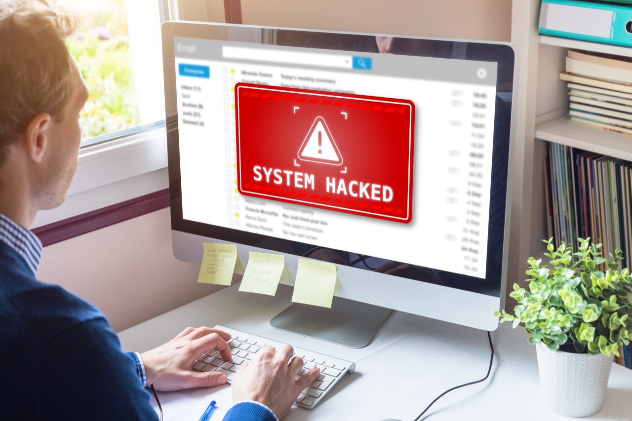 Bildschirm mit der Warnung „System hacked“, Betroffener von hinten