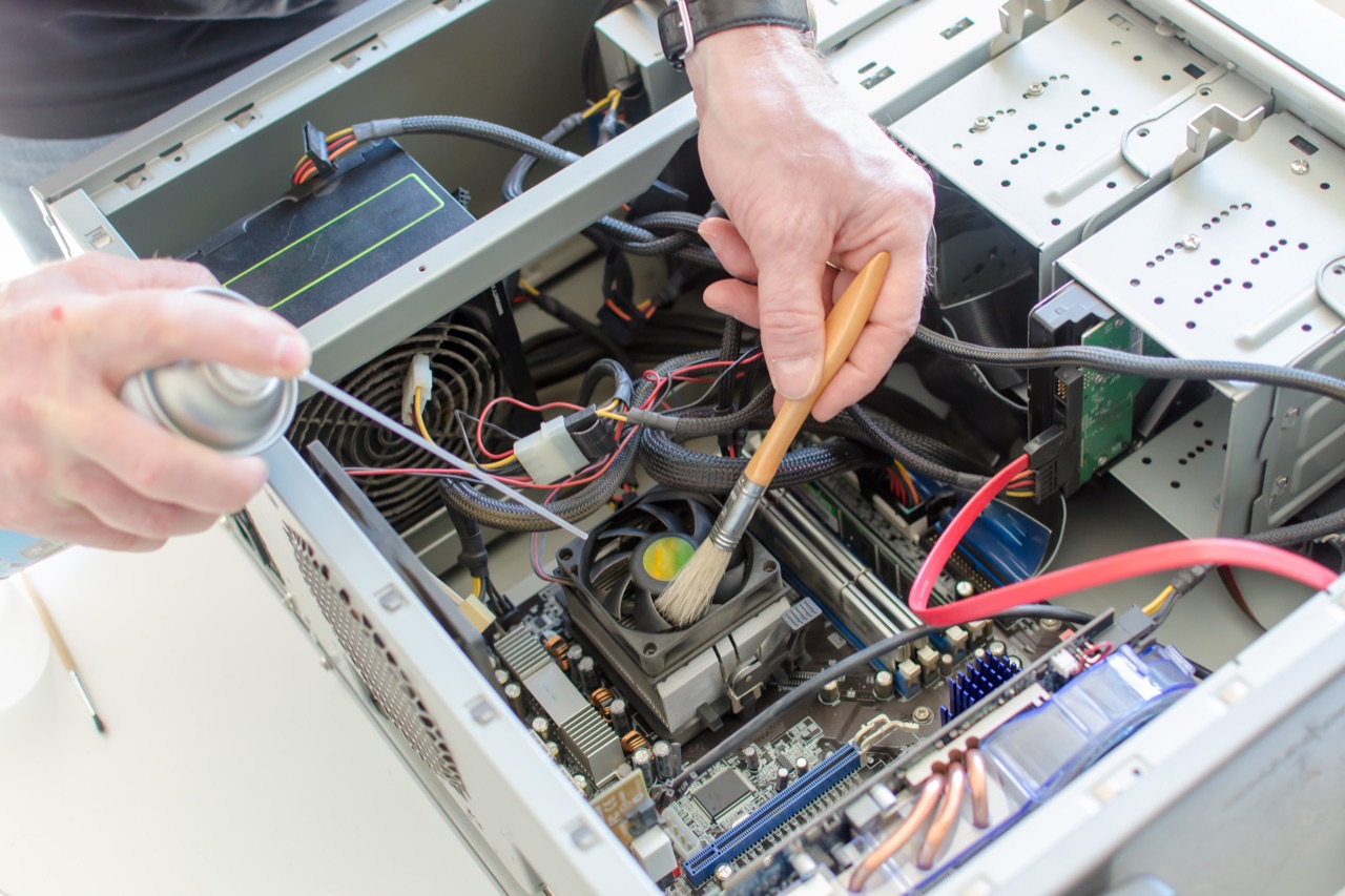 Innenreinigung eines PC-Gehäuses mit Pinsel und Druckluft
